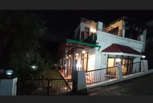 un edificio blanco con luces encendidas por la noche en Nainital Homes, en Bhowāli