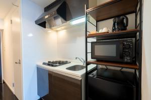 a small kitchen with a sink and a microwave at VIDA Hakata in Fukuoka