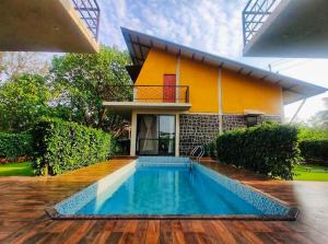 a house with a swimming pool in front of a house at Enliven Homestay Alibag, Alibaug in Nagaon