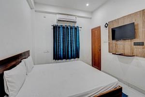 a small bedroom with a bed and a television at New divine inn in Kakarmatha