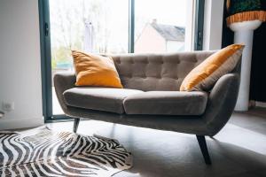 a brown couch sitting in a living room with a window at Le Gué • Élégance fonctionnelle • Parking simple in Saint-Maur