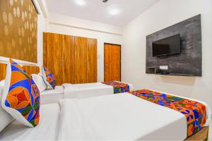 um quarto de hotel com duas camas e uma televisão de ecrã plano em FabHotel Prime Esta Inn em Pune