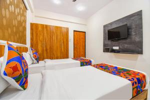 a hotel room with two beds and a flat screen tv at FabHotel Prime Esta Inn in Pune