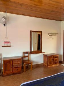 Habitación con muebles de madera, espejo y silla. en Samnang Leap guesthouse en Sen Monorom