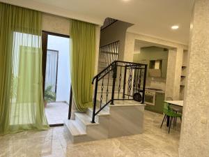 una escalera en una sala de estar con cortinas verdes en Three Palms House, en Tiflis