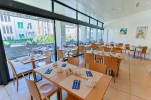 a restaurant with wooden tables and chairs and windows at Hotel Garni Muralto in Locarno