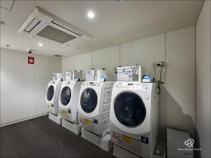 uma fila de máquinas de lavar e secar roupa numa lavandaria em Daiwa Roynet Hotel Omiya-nishiguchi em Saitama