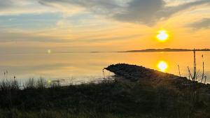 a sun setting over a body of water with a dock at Hausboot Störtebecker in Gager