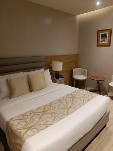 CavintiにあるCaliraya Mountain Lake Resortのベッドルーム(白い大型ベッド、テーブル、椅子付)