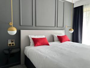 1 dormitorio con 1 cama blanca y 2 almohadas rojas en Hôtel Spa Du Béryl, en Bagnoles de l'Orne