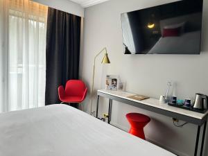 a hotel room with a bed and a red chair at Hôtel Spa Du Béryl in Bagnoles de l'Orne