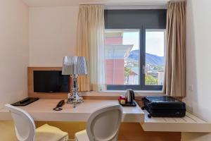 Camera con scrivania, computer e finestra. di Hotel Garni Muralto a Locarno