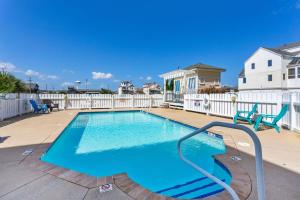 a swimming pool with two blue chairs and a white fence at SC2C Sands Shamrock Oceanfront in Kill Devil Hills