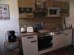 Una cocina con estufa, fregadero y microondas. en Ferienwohnung Annabelle, 15134, en Leer