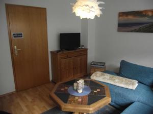 Una sala de estar con un sofá azul y una mesa. en Ferienwohnung Annabelle, 15134, en Leer
