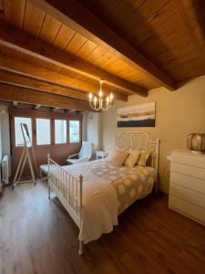 um quarto com uma cama branca e um tecto de madeira em Casa Moises en Bimenes em Bimenes