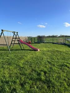 einen Spielplatz mit Rutsche auf einem Grasfeld in der Unterkunft Sosnowy Zakątek Stegna- domki letniskowe in Stegna