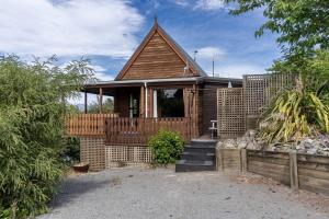 a wooden house with a porch and a fence at Welcome to the “Mountain Gem”! in Hanmer Springs