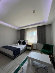 a bedroom with a bed and a green chair at Luu Hotel in Çorlu