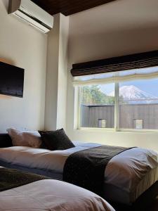 a bedroom with two beds and a window with a mountain at SWEET VILLA TAKASAMA in Fujiyoshida