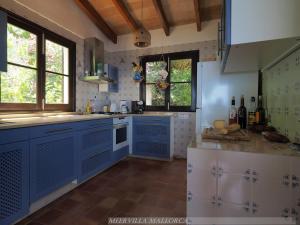 una cocina con armarios y ventanas de color azul y blanco en Meervilla Mallorca - Charmantes Ferienhaus mit phantastischem Meerblick in Canyamel, en Canyamel