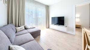 uma sala de estar com um sofá e uma televisão de ecrã plano em Apartamenty Sun & Snow Euronia em Międzyzdroje