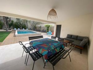 sala de estar con mesa, sillas y piscina en La Maison de l'Olivier, en Aviñón