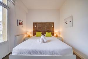 a white bedroom with a large white bed with green pillows at L'Arcachonnaise by Cocoonr in Bordeaux