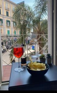 uma mesa com uma taça de batatas fritas e um copo de vinho em B&B DORIA em Nápoles