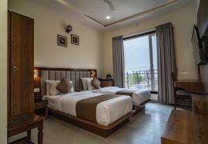 a bedroom with two beds and a large window at RABBIT RATNAM -By Udaipur Hotels in Udaipur