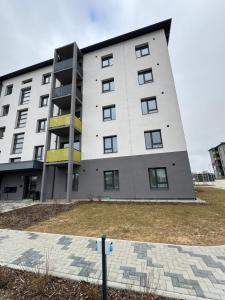 een groot wit gebouw met gele accenten bij Modern 4-Room compact flat with parking in Riga in Dreiliņi