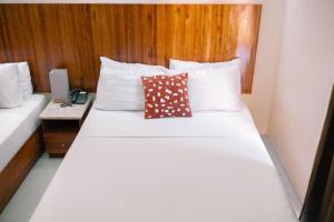 a bedroom with a white bed with a wooden headboard at Tsai Hotel and Residences in Cebu City