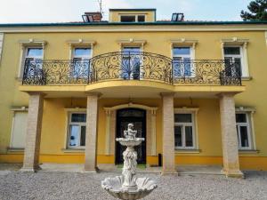 ein gelbes Gebäude mit einem Balkon und einem Brunnen in der Unterkunft Spacious Apartment near Schoenbrunn Castle in Wien