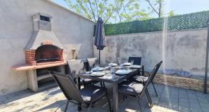 - une table et des chaises sur une terrasse avec un four extérieur dans l'établissement Beautiful Villa Casa Romito with pool in Kastelir, à Kaštelir