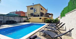- une piscine avec des chaises à côté d'une maison dans l'établissement Beautiful Villa Casa Romito with pool in Kastelir, à Kaštelir