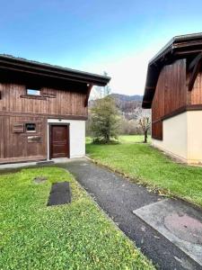 a barn with a driveway next to a building at Demi Chalet 6 personnes Samoëns in Samoëns