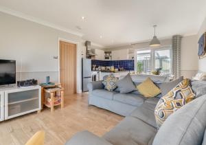 a living room with a blue couch and a kitchen at Lantic Surf in St Merryn