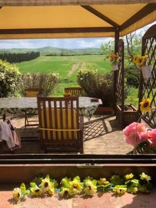 a patio with two chairs and a table and flowers at Casa Country House Girasole vakantie huis-WAKACJE HUIS in Asciano