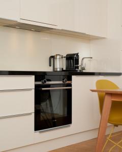 a kitchen with white cabinets and a black oven at Designer Apartment in the City Center (Naschmarkt) in Vienna