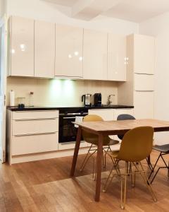 a kitchen with white cabinets and a table and chairs at Designer Apartment in the City Center (Naschmarkt) in Vienna