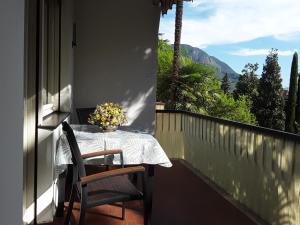 a table with a vase of flowers on a balcony at Villa Coris Ferienwohnung Magnolia in Merano