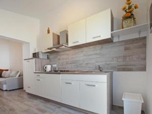 Apartment Sunset في بوريتش: مطبخ بدولاب بيضاء وقمة كونتر