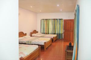 a room with three beds and a window at Royal exotic Wilpathuwa (dilsara ) in Anuradhapura