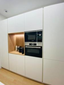 a kitchen with white cabinets and a microwave at ATSEDEN apartment aire condicionado - Opción a parking - in San Sebastián