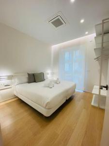 a white bedroom with a large white bed and wooden floors at ATSEDEN apartment aire condicionado - Opción a parking - in San Sebastián