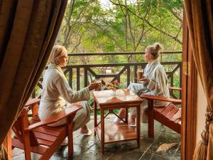 zwei Frauen sitzen an einem Tisch auf einer Veranda in der Unterkunft Fairview Hotels,Spa & Golf Resort in Tzaneen