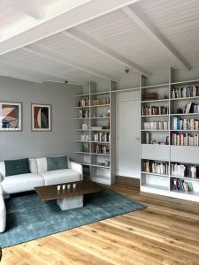 uma sala de estar com um sofá e prateleiras de livros em Charmante maison dans un coin de verdure à Boitsfort em Bruxelas