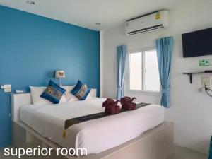 a bedroom with a large white bed with blue walls at Phannarai House in Lamai