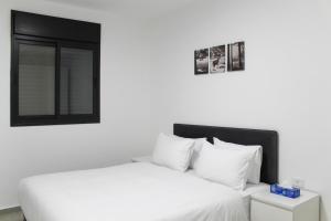 Un dormitorio con una cama con sábanas blancas y una ventana. en Luxury Suite Apartment #58 By Hashdera Eilat, en Eilat