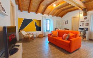 - un salon avec un canapé orange et une télévision dans l'établissement [Centro Storico] Casa con Wi-Fi e Parcheggio a 100m, à Saluces